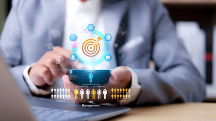 Businessman using mobile phone with virtual HR management interface. Human resource recruitment, digital teamwork, and target planning concept.