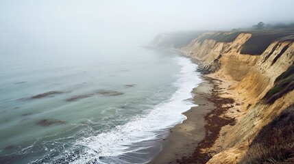 Fototapeta premium A serene coastal view shrouded in fog at a rugged shoreline.