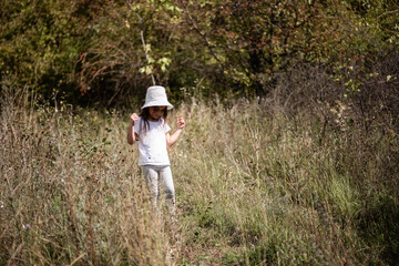 Little girl exploring nature walking through tall grass