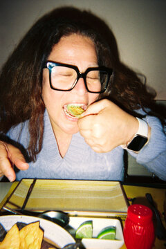 Woman eating nachos with guacamole at a restaurant
