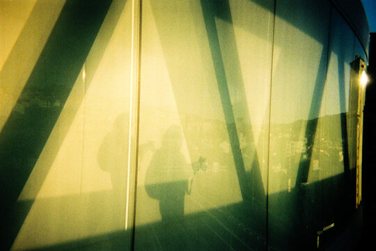 Shadow reflection of a woman with a camera on a glass wall
