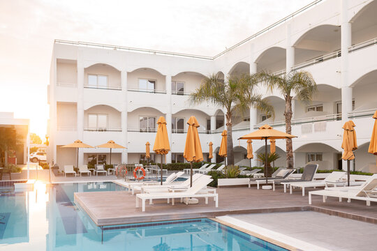 Hotel Pool Area with Deck Chairs and Umbrellas At Sunset