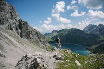 female Hiker contemplating breathtaking lake and mountain view in the alps