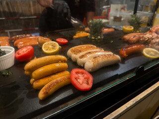 Close up Grilled Sausages and Vegetables on Hot Plate at Night Market Food Stall