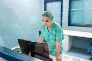 Female surgeon using computer in operating room control room