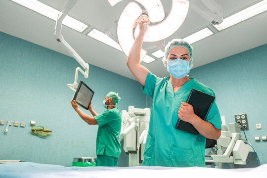 Surgeons preparing operating room for surgery with surgical lights