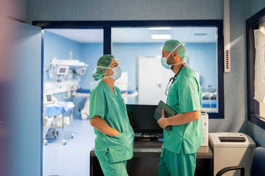Surgeons wearing surgical mask talking in operating room doorway