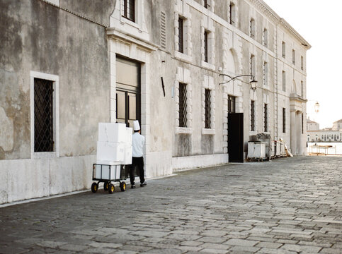 Chef in uniform drags a cart in the streets of Venice