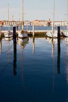 Moored boats, their reflections in the water and Venice on background
