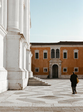 Unrecognizable man walks in the sun on parvis in front of church