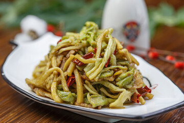 Stir-fried pork belly with gongcai served in a white porcelain plate