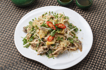 Spicy shredded chicken in a fan-shaped white porcelain plate placed on a placemat