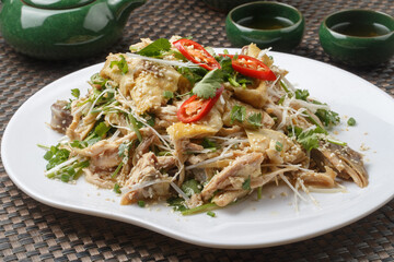 Spicy shredded chicken in a fan-shaped white porcelain plate placed on a placemat