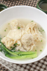 Wontons in a white porcelain bowl are placed on a placemat