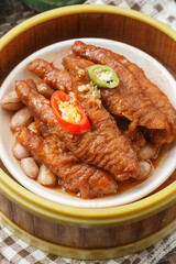 Steamed chicken feet in a basket are placed on a tablecloth