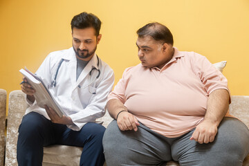 Male indian doctor consulting with overweight patient. Healthcare worker advice obese man to lose weight and discuss health risks of overweight. Obesity and Diabetes.