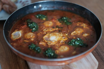 Skillet of Shakshuka on Wooden Board on Table