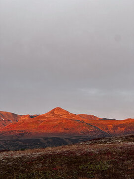 Fiery sunset light on rugged mountain peak