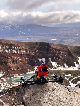 FPV drone on cliff above frozen crater lake