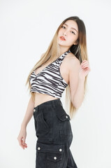 Half body fashion asian pretty young woman model poses confidence charming wear zebra print halter top, black cargo pants, showcasing trendy streetwear style, creative against white background studio.