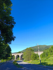 A road with a bridge in the background and trees on both sides
