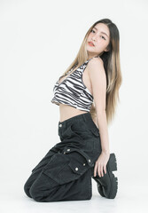 Fashion asian attractive pretty young woman model poses confidence wear zebra print halter top, black cargo pants, look at camera sit showcase trendy streetwear style, creative white background studio