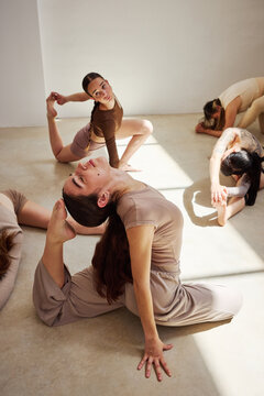 Multiple dancers practicing yoga poses in a studio during daylig