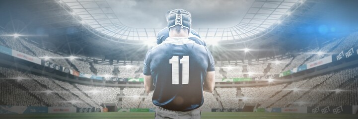 Rear view of caucasian male player wearing 11 number jersey standing in illuminated stadium
