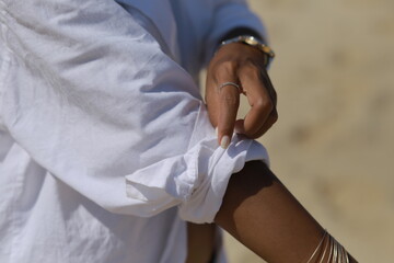 Woman Rolling Up Sleeve of White Shirt on the Beach