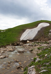 the sources of a mountain river high in the mountains on alpine meadows during the melting of snow,...