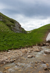 the sources of a mountain river high in the mountains on alpine meadows during the melting of snow,...