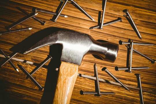 Fototapeta Claw hammer is lying flat on wood-grain work surface with scattered steel nails, flat design