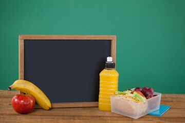 Empty blackboard with fruits and bottle on table