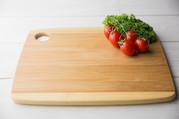Tomatoes with parsley and chopping board on hardwood floor