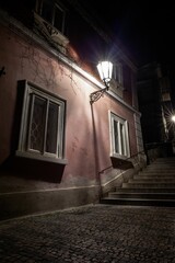 wrought-iron lamp casting shadows on stucco latticed windows above cobblestones, railed stairs