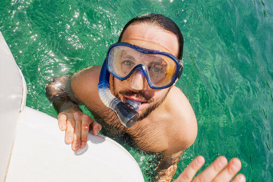 Man snorkeling in clear water enjoying a sunny day by the boat