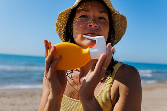 Woman holding sunscreen lotion on beach for sun protection
