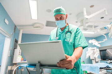 Surgeon using laptop in operating room wearing surgical mask