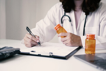 A female doctor reviews test results and diagnoses disease, records, prescribes medicine, and...