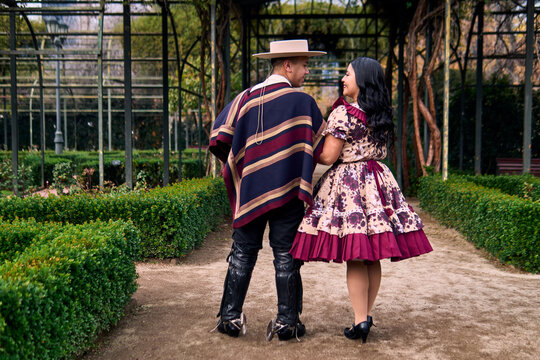 A couple of young Chilean Latin cuecas dancers, walking romantically back to back, gazing affectionately at each other. Chilean Independence Day celebration.