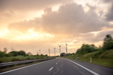 Highway at sunset. Wind turbines in background. Motion blur effect.