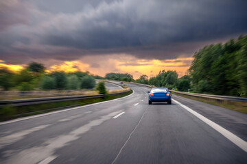 High speed driving. Blue car on highway. Sunset road scene