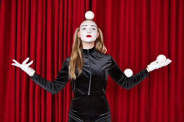 A mime artist works on a theatre stage with white balls.