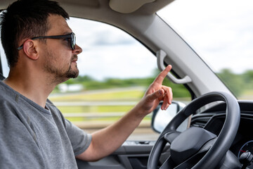 Driver gesturing with finger. Man driving car. Emotional reaction in motion.