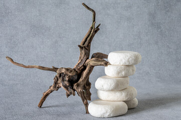 Empty stone podium, pieces of snag on grey background. Minimalist eco backdrop. Round natural rocks and snags. Pedestal for product advertising. Wabi sabi concept. Copy space, front view.