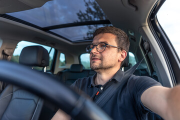 Man driving car. Focused driver in daylight. Calm modern interior.