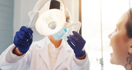 Woman, dentist and light for checkup at clinic for dental care, tooth cleaning and medical...