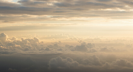 Obraz premium Sunset sky with golden sunlight breaking through thick fluffy clouds during late evening or early night over a vast sky with warm tones and dramatic cloud formations.