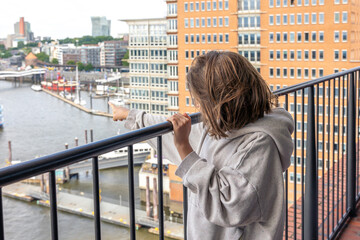 Child on balcony. Pointing at harbor. City view.