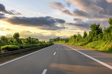 Empty highway in greenery. Forest road. Sunset light